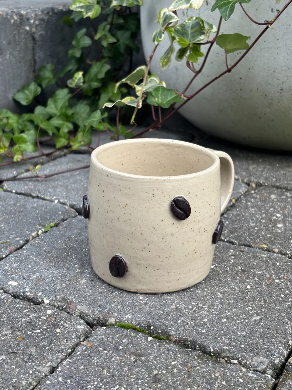 Ljus mugg med pålagda kaffebönor.