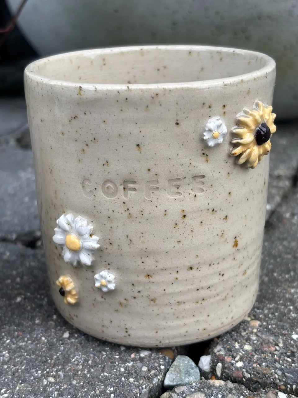Mugg med ordet COFFEE instämplat och pålagda blommor.